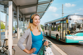 Junge Frau mit Kopfhörer an RSVG-Bushaltestelle