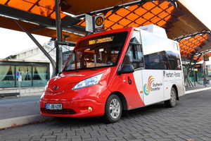 Ein rot-weißer Bürgerbus des Bürgerbusvereins Emsdetten steht an einer Bushaltestelle.